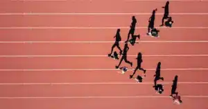 Vertriebserfolg trainieren wie Profisport: Das Bild zeigt Läufer auf einer Laufbahn aus der Vogelperspektive. Jeder Athlet verfolgt sein eigenes Tempo und Ziel – genau wie erfolgreiche Vertriebsteams, die mit Disziplin, Ausdauer und kontinuierlichem Training Spitzenleistungen erreichen. Die roten Bahnen symbolisieren klare Prozesse, strategische Planung und den Fokus auf messbare Ergebnisse im Vertrieb. Wer seinen Vertriebserfolg trainieren wie Profisportler möchte, setzt auf regelmäßiges Coaching, Leistungsanalysen und konsequente Weiterentwicklung statt auf kurzfristige Erfolge.